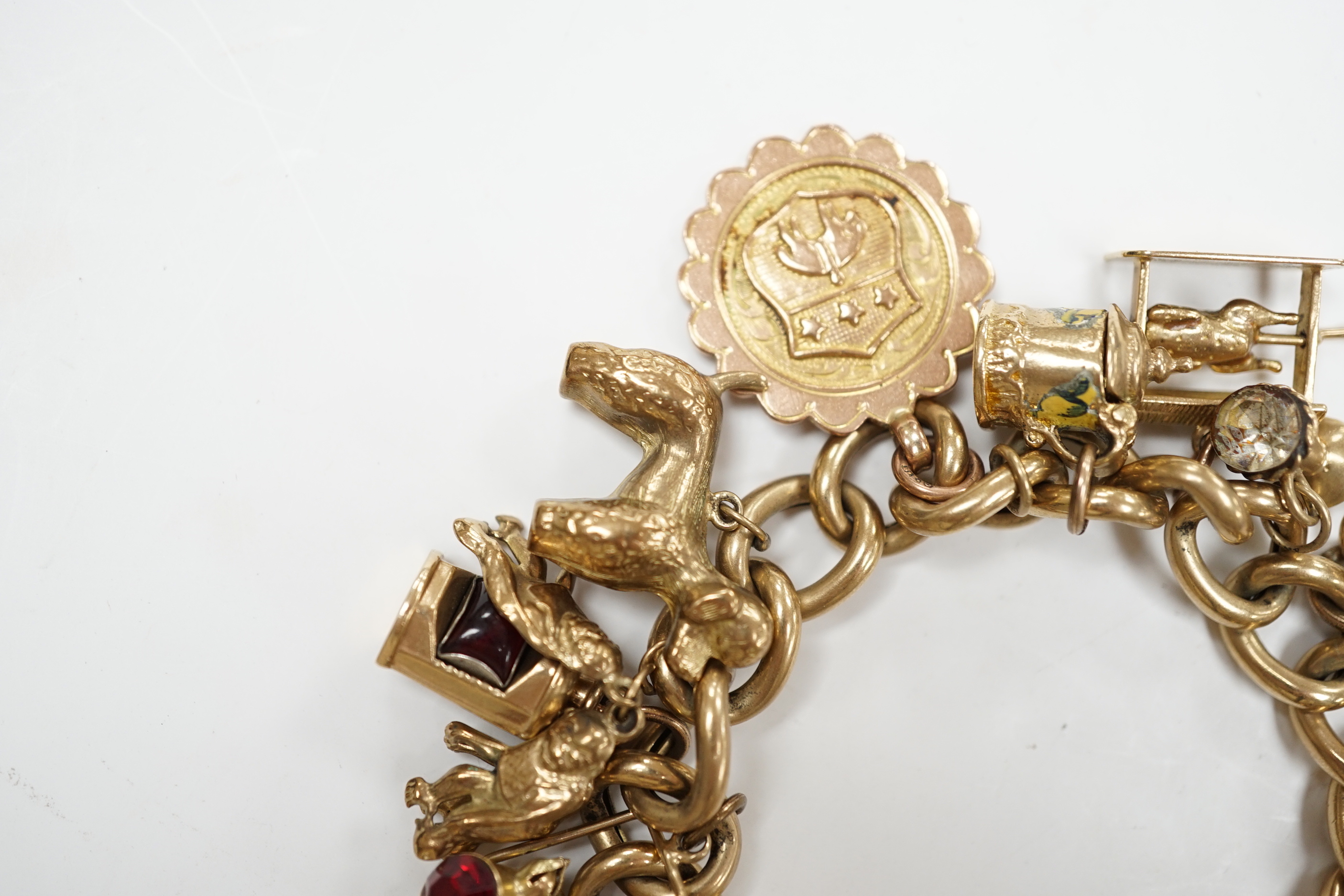 An early 1960's 9ct gold curb link charm bracelet, hung with fifteen assorted charms, including twelve 9ct gold, gross weight 49.7 grams.